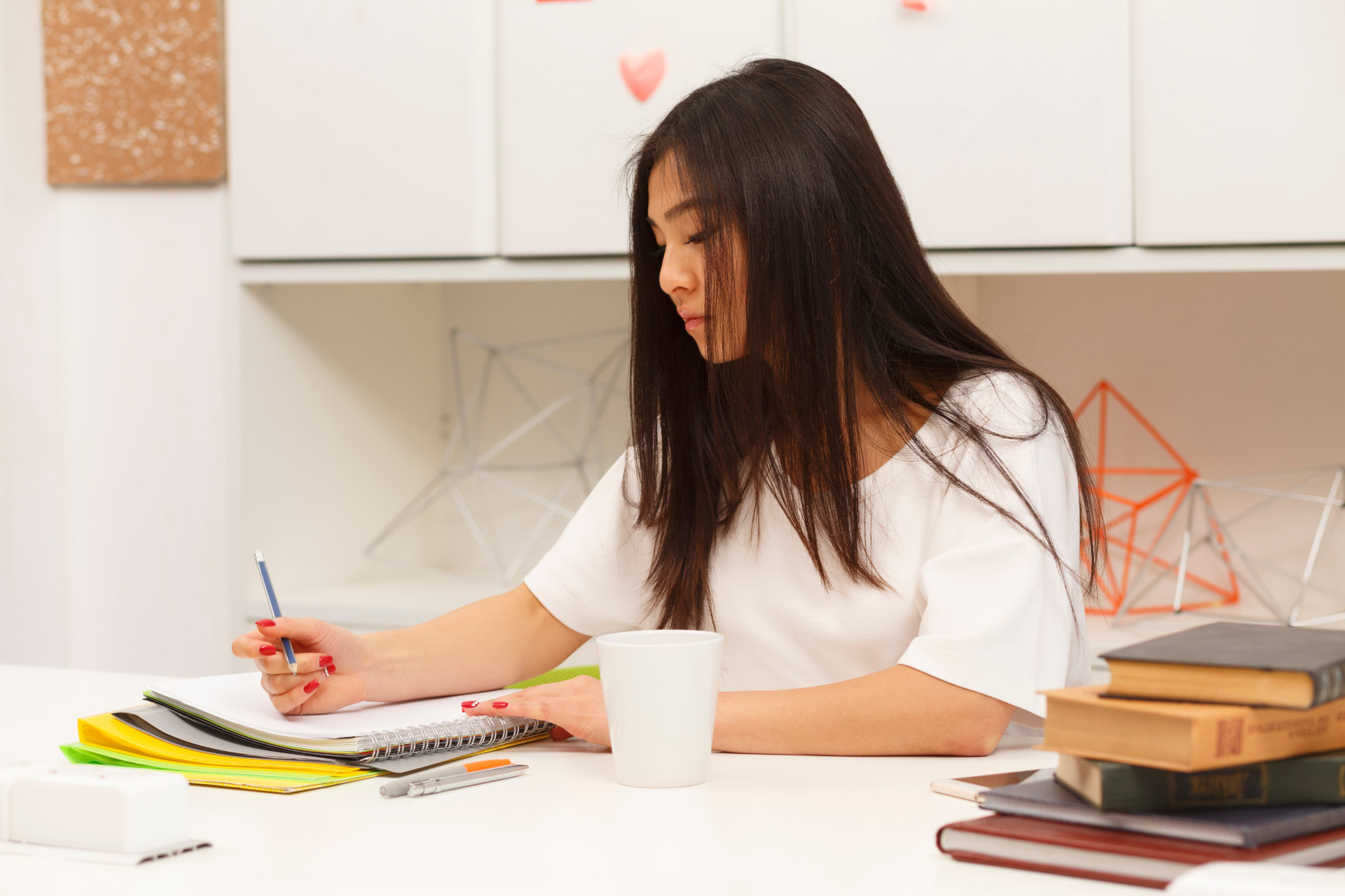 asian student writing something her exercise book drinking delicious cup tea coffee library